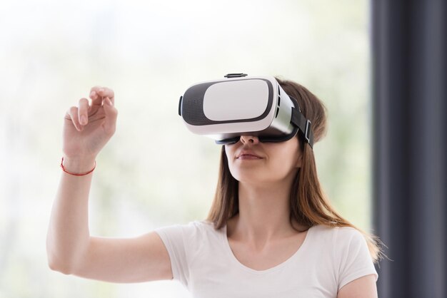 Mulher sorridente e feliz obtendo experiência usando óculos de realidade virtual com fone de ouvido VR em casa