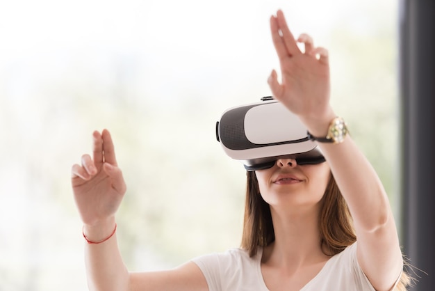 Mulher sorridente e feliz obtendo experiência usando óculos de realidade virtual com fone de ouvido VR em casa