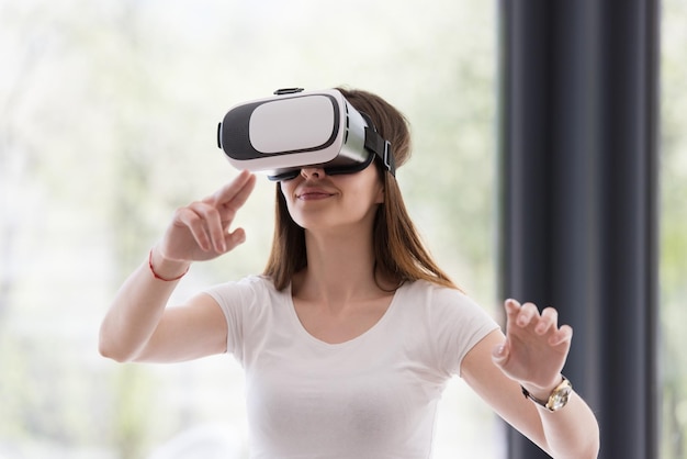 Mulher sorridente e feliz obtendo experiência usando óculos de realidade virtual com fone de ouvido VR em casa