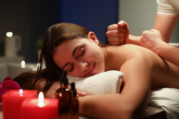 Mulher sorridente e relaxada recebendo massagem profissional no centro de spa