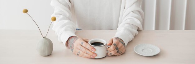 Mulher sorridente e tatuada tomando um café