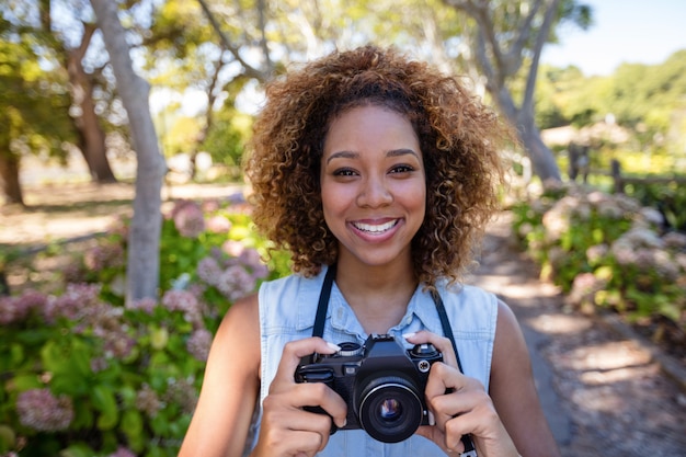 Foto mulher sorridente em pé com câmera digital