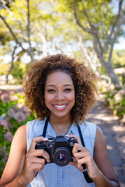 Foto mulher sorridente em pé com câmera digital