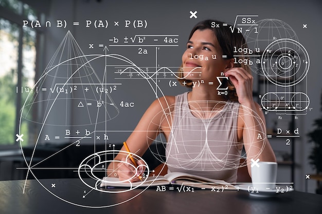 Foto mulher sorridente em roupas casuais, anotando no caderno no local de trabalho do escritório com uma xícara de café conceito de educação empresarial distante tecnologia da informação sonhando pensando desenhos matemáticos