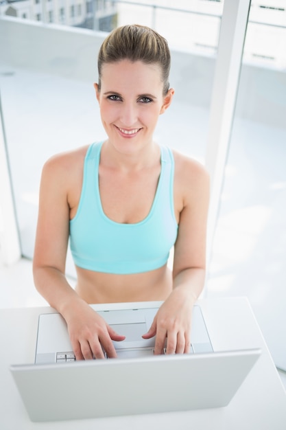 Mulher sorridente em roupas esportivas usando laptop