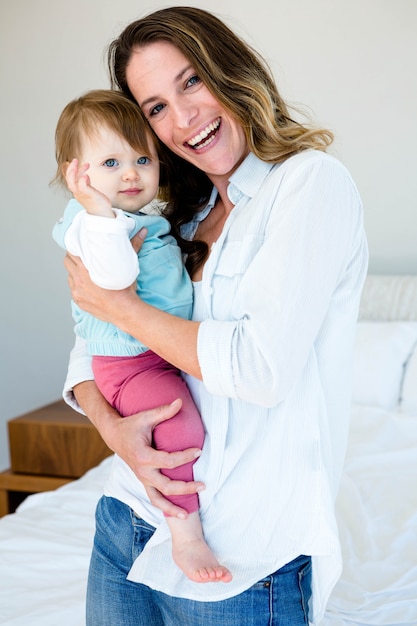 Mulher sorridente em um quarto segurando um bebê adorável