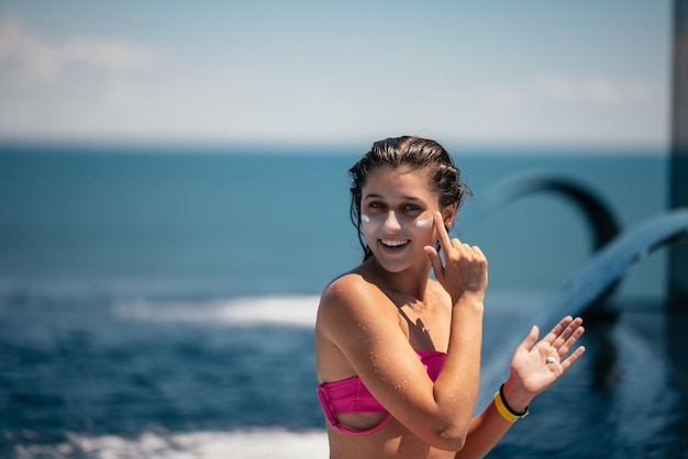 Mulher sorridente está aplicando protetor solar no rosto