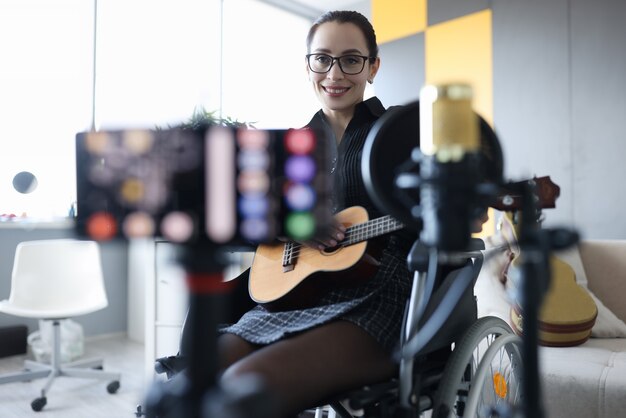 Mulher sorridente está gravando violão tocando aulas online para ensinar o conceito de música