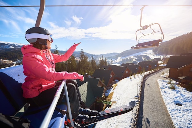 Mulher sorridente está sentada no teleférico em resorts de montanha