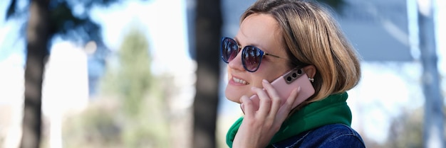 Mulher sorridente falando ao telefone em comunicação remota de rua com o conceito de amigos