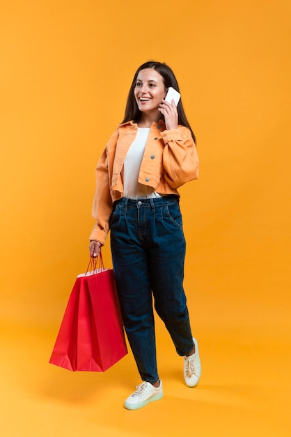 Foto mulher sorridente falando ao telefone enquanto segura sacolas de compras