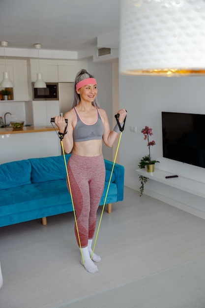 Mulher sorridente fazendo exercício com corda elástica de fitness