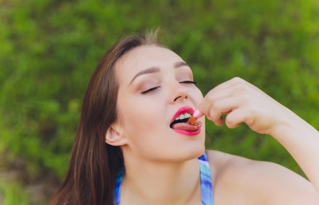 Foto mulher sorridente fazendo uma pausa relaxante para o almoço ao ar livre, ela está sentada na grama e comendo