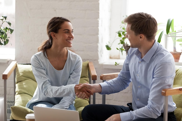 Mulher sorridente, feliz, apertando a mão de um empresário confiante, conhecendo um novo parceiro de negócios, fazendo um negócio, cumprimentando, apresentando ao cliente, negociando um acordo bem sucedido.