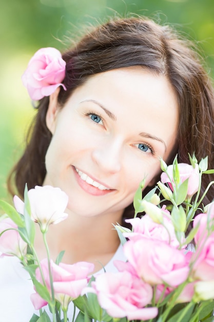 Mulher sorridente feliz com lindas flores contra o fundo verde da primavera