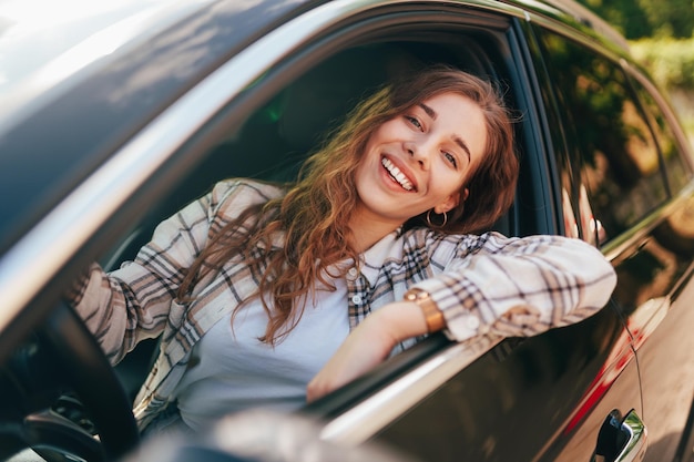 Mulher sorridente feliz dentro de um carro a conduzir na rua