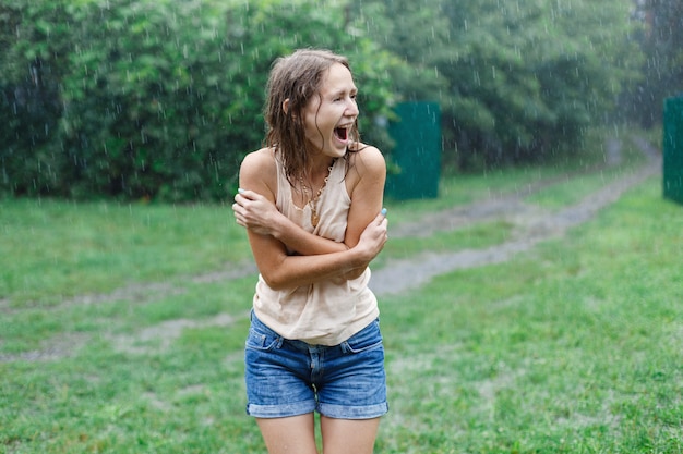 Mulher sorridente feliz sob chuva de verão