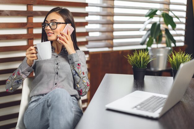 Mulher sorridente feliz trabalhando com laptop e bebendo café