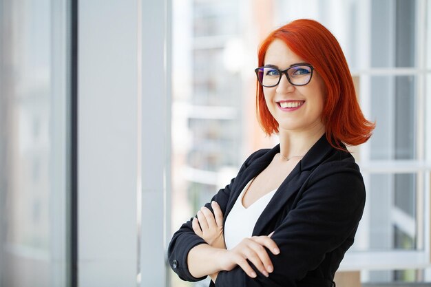 Mulher sorridente freelancer com cabelo vermelho trabalhando com laptop