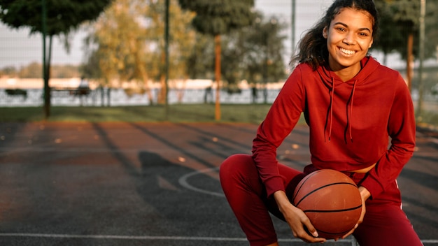 Mulher sorridente jogando basquete ao ar livre