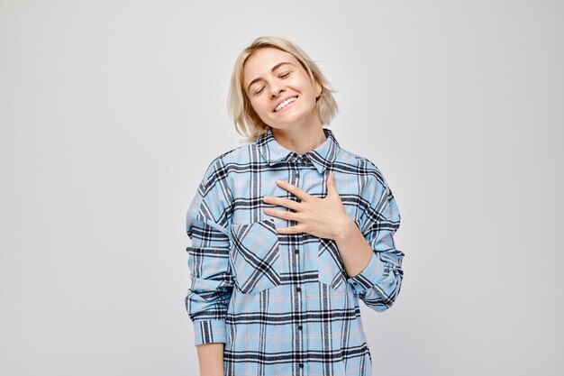 Mulher sorridente mão no peito emoção de gratidão em fundo branco