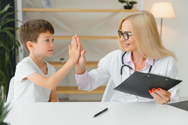 Mulher sorridente, médica ou enfermeira, dá mais cinco ao paciente menino animado na consulta na clínica, criança pequena feliz, divirta-se cumprimentando com pediatra feminina no conceito de saúde hospitalar