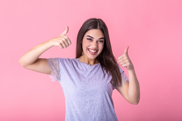 Mulher sorridente, mostrando os polegares e olhando para a câmera