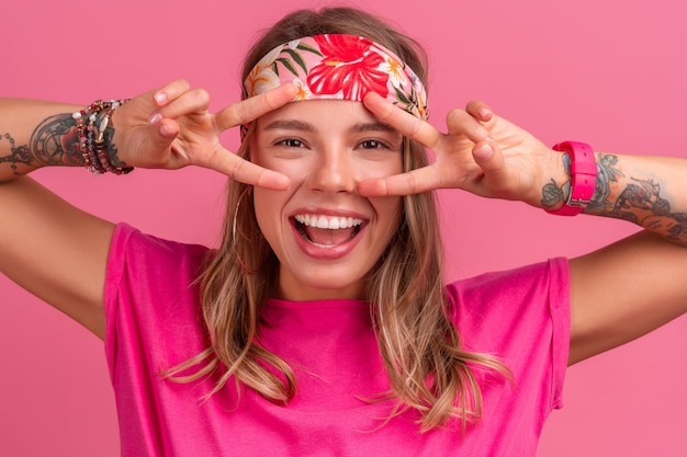 Mulher sorridente muito fofa em uma camisa rosa boho hippie acessórios sorrindo diversão emocional posando em rosa isolado