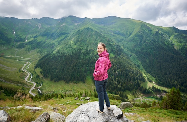 Mulher sorridente na rocha na natureza paisagem montanhas e florestas