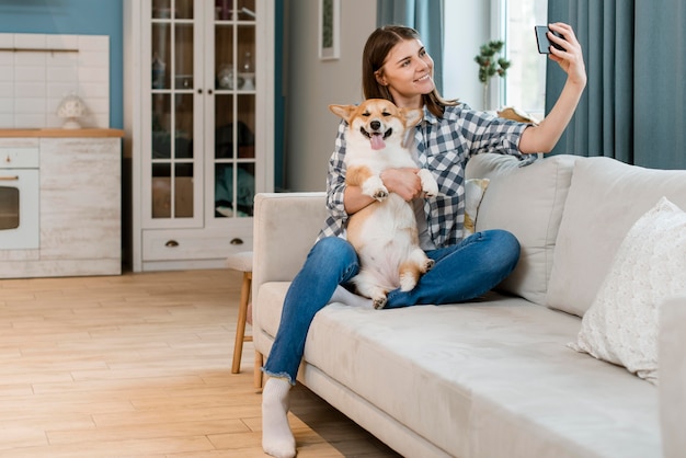 Mulher sorridente no sofá tomando selfie com seu cachorro