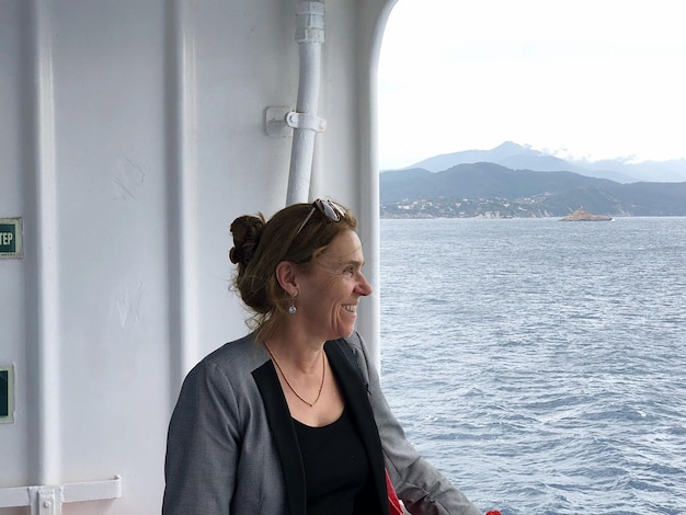 Foto mulher sorridente olhando para o mar em um barco