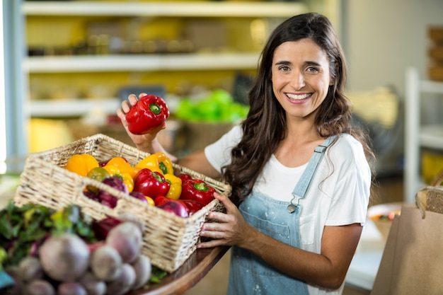 Foto mulher sorridente pegando pimentão na cesta do supermercado