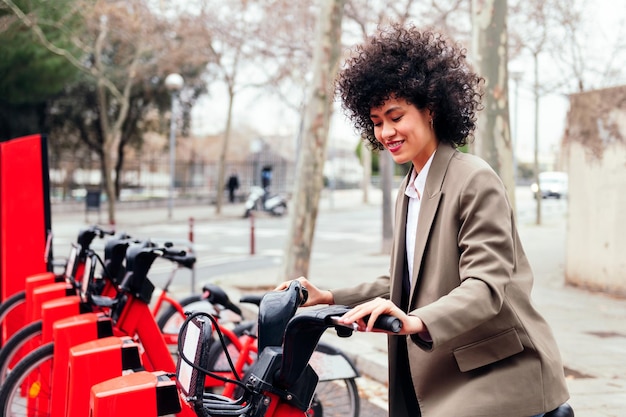 Mulher sorridente pegando uma bicicleta da estação de aluguel