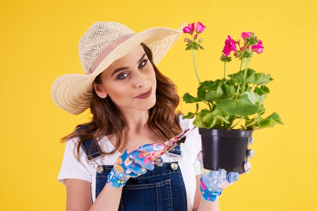 Mulher sorridente podando flores em vaso de flores