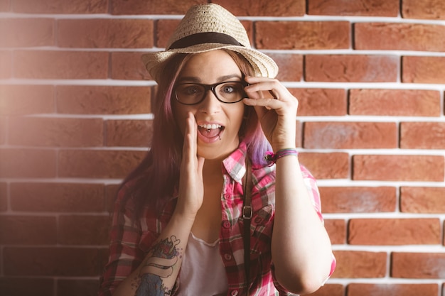 Mulher sorridente posando contra a parede de tijolos