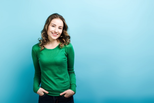 Mulher sorridente posando de suéter verde.