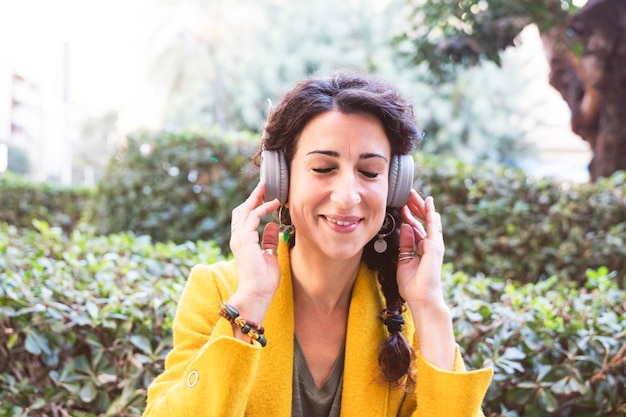 Mulher sorridente segura fones de ouvido na cabeça