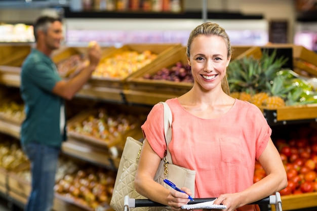 Mulher sorridente segurando a lista de compras