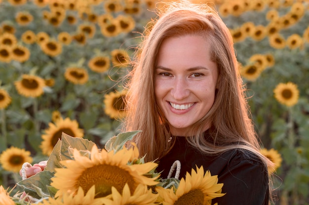 Foto mulher sorridente segurando girassóis