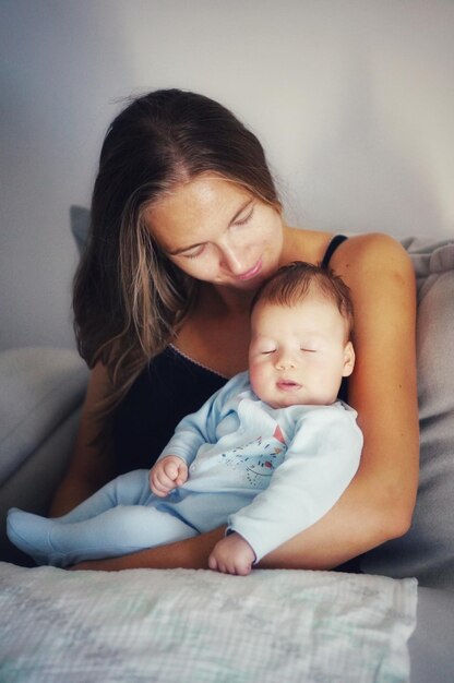 Foto mulher sorridente segurando o filho na cama em casa