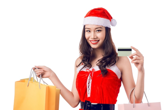 Mulher sorridente segurando sacolas de compras antes do natal mostrando cartão de crédito