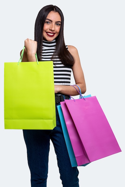 Mulher sorridente segurando sacolas de compras, isoladas em um fundo branco.