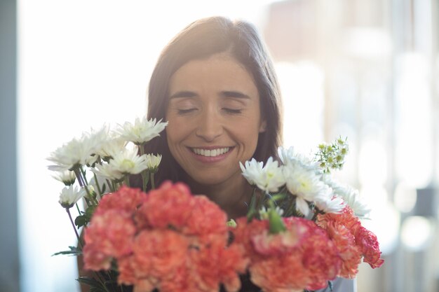 Mulher sorridente segurando um buquê com os olhos fechados