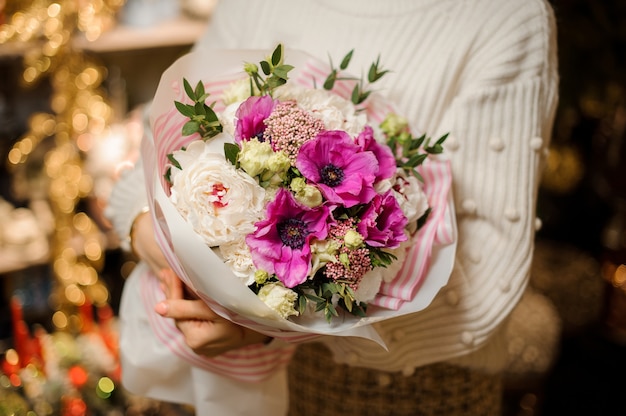 Mulher sorridente segurando um buquê de flores delicadas de cor rosa e roxo