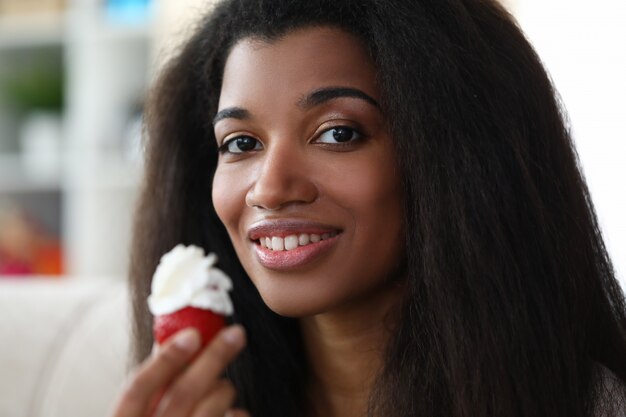 Mulher sorridente segurando um morango com creme