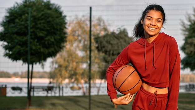 Mulher sorridente segurando uma bola de basquete com espaço de cópia
