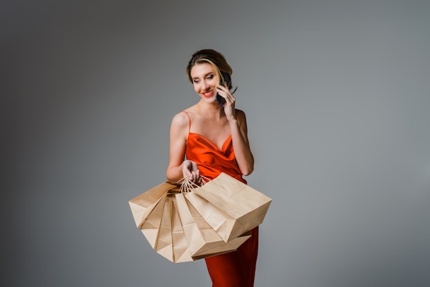 Mulher sorridente segurando uma bolsa e um celular