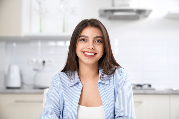 Mulher sorridente sentada na cozinha