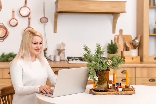 Mulher sorridente, sentada, navegando na internet em um laptop em casa,