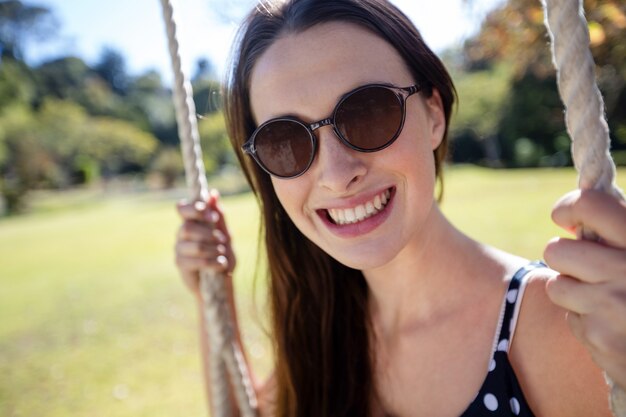 Mulher sorridente, sentado no balanço no parque